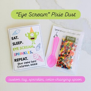 May include: A whimsical set featuring a custom tag with the text "Eye Scream" Pixie Dust, a green monster illustration, and a pink spoon. The set includes a packet of rainbow sprinkles and a spoon that changes color when cold.
