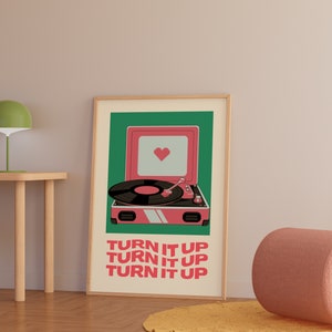 May include: A pink record player with a heart on the speaker and the text "TURN IT UP" repeated three times. The record player is on a green background.