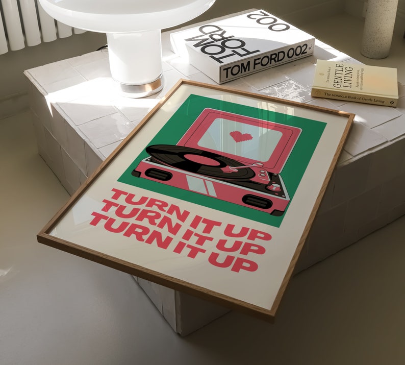 May include: A framed print with a retro-style record player on a green background. The record player is pink with a white record on it. The text "TURN IT UP" is repeated three times in pink letters.
