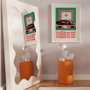 May include: A white framed print with a green background and a pink record player with a heart on the speaker. The text on the print reads "Turn it up, Turn it up, Turn it up".