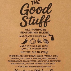 May include: A brown paper package of "The Good Stuff" all-purpose seasoning blend. The label includes the text "Handcrafted in Michigan" and lists ingredients like paprika, chili powder, and mustard seed. Net weight is 3.5 oz (99g).