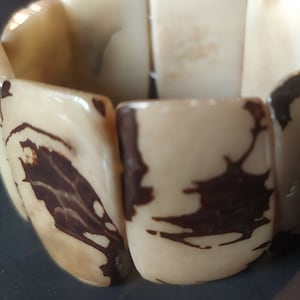 Peut inclure: Gros plan sur un bracelet composé de perles rectangulaires à motifs brun clair et brun foncé.