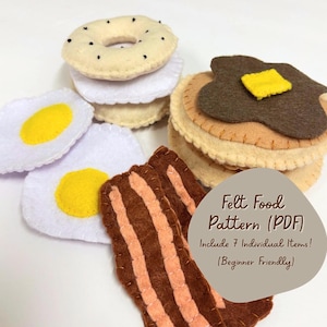 May include: A collection of felt food items, including a bagel, pancakes with butter, fried eggs, and bacon strips. The items are made of various colors of felt and are arranged on a white surface. The image includes text that says "Felt Food Pattern (PDF)"