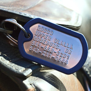 K&ouml;nnte beinhalten: Blauer Metall-Hundeanh&auml;nger mit dem Text "ROCCO UPPER OLALLA ROSEBURG, OR 841-668-3201 843-211-0644"