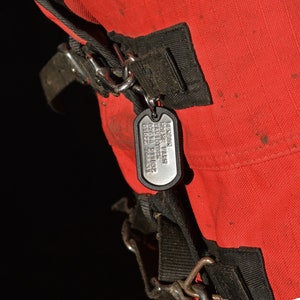 K&ouml;nnte beinhalten: Ein silbernes Hundehalsband mit dem Text "Benson Home Park Livestock 01622 918632 74451" an einem roten Beutel mit schwarzen Riemen.