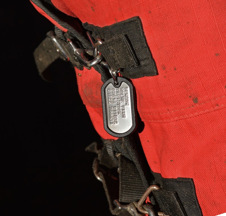 K&ouml;nnte beinhalten: Ein silbernes Hundehalsband mit dem Text "Benson Home Park Livestock 01622 918632 74451" an einem roten Beutel mit schwarzen Riemen.