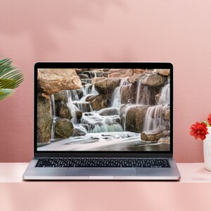 Waterfall Print wall art instant download of a soft waterfall gently flowing over the rocks in a mockup of the image being used as wallpaper on a laptop computer.