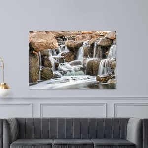 Waterfall Print wall art instant download of a soft waterfall gently flowing over the rocks in a mockup of the image printed on a metal and hanging over a sofa.