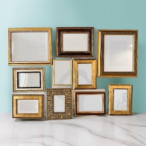 May include: A selection of ten picture frames in various sizes and styles. The frames are mainly gold and brown, with decorative detailing. The frames are arranged against a light blue backdrop.