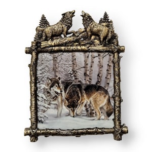 Peut inclure: Une image encadrée de trois loups dans une forêt enneigée. Le cadre est en bois et a un aspect rustique. Les loups sont au premier plan de l'image, et la forêt est en arrière-plan. L'image est dans un cadre de couleur or.