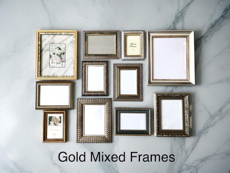 May include: An assortment of gold and mixed-metal picture frames in different sizes and designs, displayed on a marble-effect wall. The frames feature both elaborate and plain styles, some with pictures. The text "Gold Mixed Frames" is at the bottom.