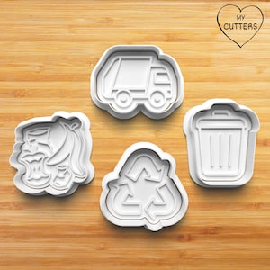 Könnte beinhalten: Ein Set aus vier weißen Kunststoff-Ausstechformen, bestehend aus einem Müllwagen, einer Mülltonne, einem Recycling-Symbol sowie einer Bananenschale mit Apfelgehäuse. Jede Form hat einen erhöhten Rand und ein herzförmiges Logo mit der Aufschrift MY CUTTERS.