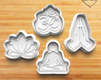 Könnte beinhalten: Ein Set aus vier weißen Ausstechformen aus Kunststoff, die eine Lotusblume, ein Om-Symbol, eine sitzende Meditationsfigur und zwei gefaltete Hände in Gebetshaltung zeigen. Der Text MY CUTTERS ist in einer Herzform abgedruckt.