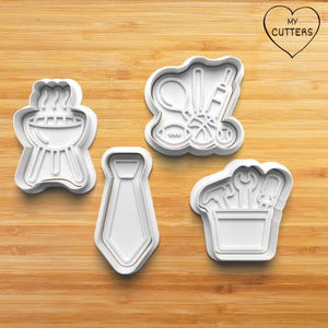 Könnte beinhalten: Vier weiße Ausstecher aus Kunststoff auf einer Holzoberfläche. Die Ausstecher sind in Form eines Grills, von Sportgeräten, einer Krawatte und einer Werkzeugkiste gehalten. Der Text "MY CUTTERS" befindet sich in einer Herzform.