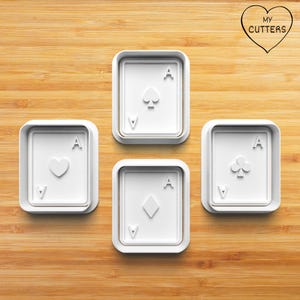 Könnte beinhalten: Ein Set aus vier weißen Kunststoff-Ausstechformen in Form von Spielkarten, die jeweils ein anderes Symbol zeigen: Herz, Pik, Karo und Kreuz. Jede Form hat den Buchstaben A in den Ecken eingeprägt. Ein herzförmiges Logo mit dem Text MY CUTTERS.