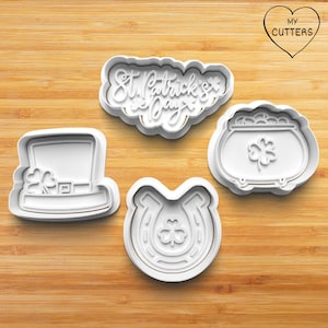 May include: Set of four white plastic cookie cutters shaped like a leprechaun hat, a horseshoe, a pot of gold, and the words "St. Patrick's Day".