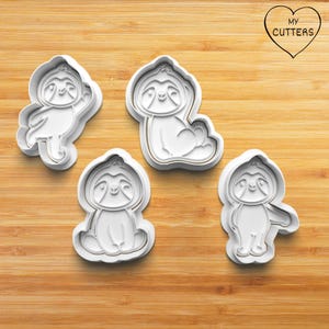 Può includere: Un set di quattro tagliabiscotti in plastica bianca a forma di bradipi in varie pose. Ogni stampo presenta il contorno dettagliato del viso e del corpo di un bradipo. Il testo MY CUTTERS è stampato all'interno di un cuore.