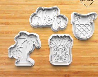 Puede incluir: Conjunto de cuatro cortadores de galletas de plástico blanco, que representan una palmera, una máscara tiki, una piña con una pajita y la palabra "Aloha".