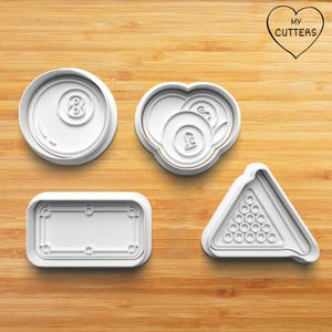 Könnte beinhalten: Vier weiße Ausstecher aus Kunststoff in Form von Billard-Objekten. Enthält einen Kreis mit der Zahl 8, ein Herz mit zwei Billardkugeln, einen rechteckigen Tisch und ein Dreieck mit 15 Kugelpositionen. Der Text "MY CUTTERS" befindet sich in Herzform.