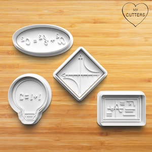 Könnte beinhalten: Vier weiße Ausstecher aus Kunststoff in verschiedenen Formen, die jeweils ein mathematisches Symbol oder eine Gleichung darstellen. Die Ausstecher umfassen ein Oval, eine Raute, eine Glühbirne und ein Rechteck. Das Bild enthält auch ein Herz mit dem Text "MY CUTTERS".