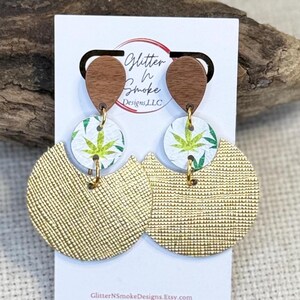 Pendientes redondos de cuero con hojas doradas y colgantes de madera dorada.