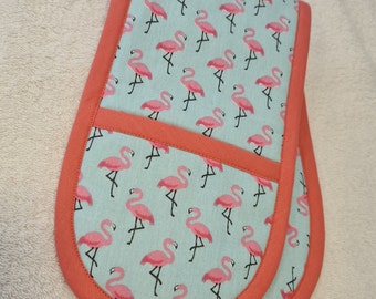 May include: A pair of teal blue oven mitts with a flamingo print and coral orange trim.