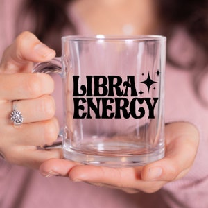 May include: A clear glass mug with a black design that says "LIBRA ENERGY" with stars on the side.