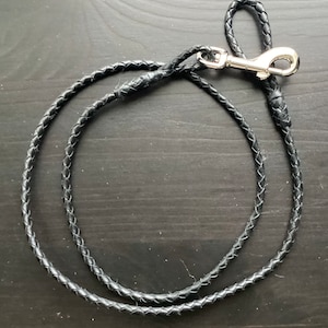 May include: A black leather braided dog lead with a silver clip.