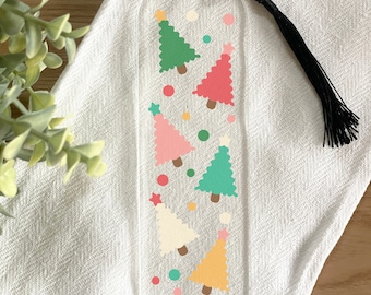 Könnte beinhalten: Transparenter Acryl-Lesezeichen mit bunten Weihnachtsbäumen in Grün, Rosa, Rot, Gelb und Creme, jeder mit einem Stern. Das Lesezeichen hat eine schwarze Quaste und bunte Punkte. Ein festliches Accessoire für Bücherliebhaber.