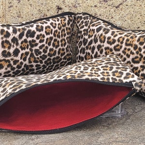 May include: Three leopard print cosmetic bags with red zipper pulls. The bags are lined with red fabric and have a zipper closure.