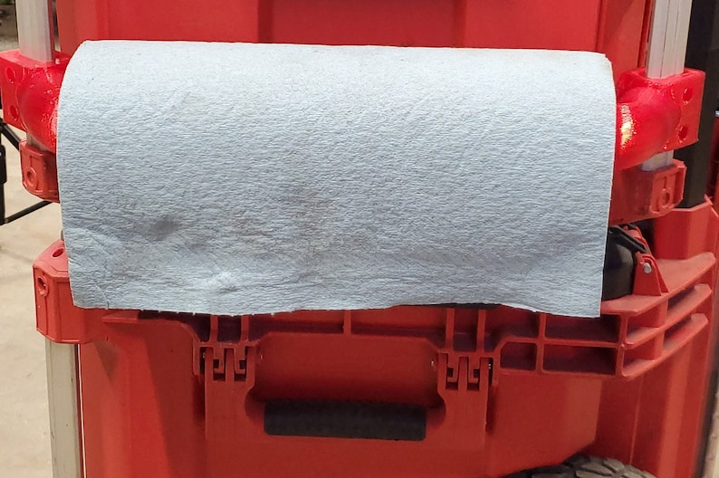 Puede incluir: Una caja de herramientas roja con un pa&ntilde;o gris que cubre la parte superior. La caja de herramientas tiene un asa y un pestillo.