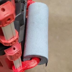 Puede incluir: Caja de herramientas roja y plateada con un asa roja impresa en 3D y un rodillo de espuma gris sujeto al asa.