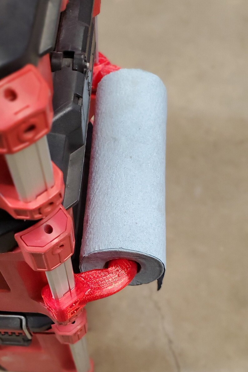 Puede incluir: Caja de herramientas roja y plateada con un asa roja impresa en 3D y un rodillo de espuma gris sujeto al asa.
