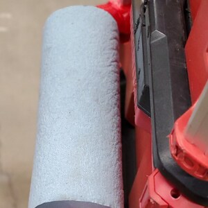 Puede incluir: Una caja de herramientas roja y negra con un asa de espuma gris. El asa est&aacute; unida a la caja con un soporte de metal rojo.