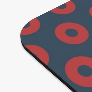 May include: A blue mouse pad with a repeating pattern of red donuts. The donuts have a white center.