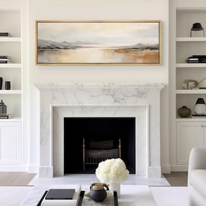 May include: A white marble fireplace with a black fireplace insert. A framed landscape painting hangs above the fireplace. A white vase with white flowers sits on a coffee table in front of the fireplace.