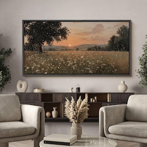Puede incluir: Una impresi&oacute;n de arte mural rectangular de paisaje que muestra un atardecer sobre un campo de flores silvestres blancas y hierba alta, con un &aacute;rbol grande a la izquierda y colinas en la distancia, enmarcada con un borde negro fino en la pared.