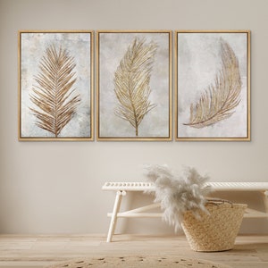May include: Set of three framed prints featuring gold leaf palm leaves on a white background. The prints are in gold frames and are arranged in a row.