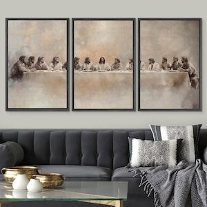 May include: A set of three framed canvas prints showing the Last Supper. The sepia-toned artwork depicts Jesus and his disciples seated at a table. The prints are displayed above a dark grey sofa with decorative cushions and gold bowls.
