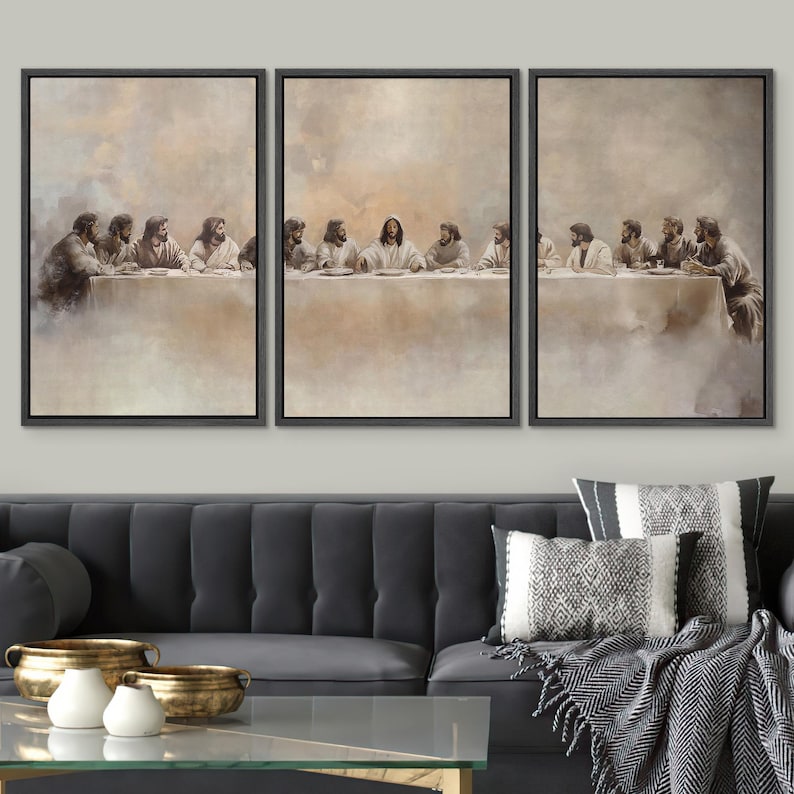 May include: A set of three framed canvas prints showing the Last Supper. The sepia-toned artwork depicts Jesus and his disciples seated at a table. The prints are displayed above a dark grey sofa with decorative cushions and gold bowls.