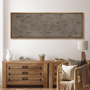Puede incluir: Una obra de arte rectangular en lienzo con un marco de madera marr&oacute;n. La obra presenta un fondo gris apagado con numerosas siluetas de peces grises. La obra se exhibe sobre una c&oacute;moda de madera.
