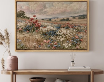 May include: A rectangular framed landscape painting depicting a field of wildflowers including red poppies, white daisies, and blue cornflowers set against a rolling countryside under a cloudy sky. The artwork is enclosed in a light wood frame.