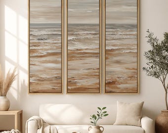 May include: A triptych wall art set featuring three vertical framed canvases depicting a coastal landscape with textured brushstrokes in shades of beige, tan, white, and muted gray, showing ocean waves meeting a sandy shoreline.