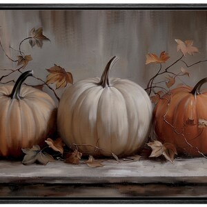 May include: A framed painting featuring three pumpkins in varying shades of orange and white. The pumpkins are arranged on a wooden surface, with dried leaves and vines adding autumnal detail. The background is a muted, neutral tone.