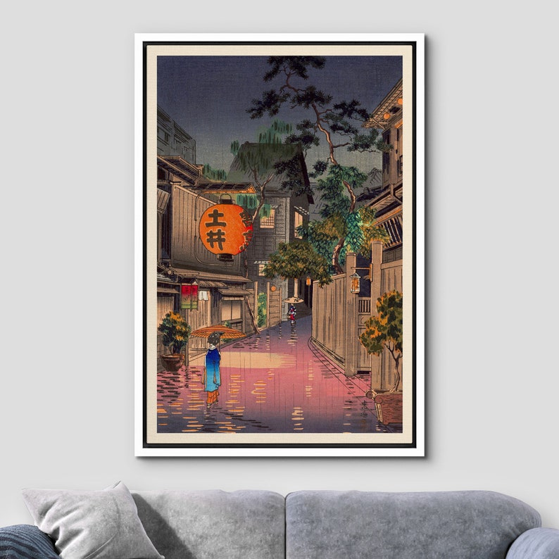May include: A Japanese woodblock print depicting a rainy night scene in a narrow street. The street is lined with traditional Japanese buildings and lanterns. A woman with an umbrella walks down the street.
