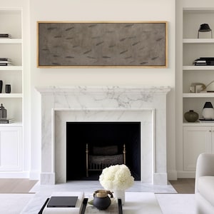 Puede incluir: Obra de arte rectangular enmarcada con peces sobre un fondo gris, sobre una chimenea de m&aacute;rmol blanco. La habitaci&oacute;n tiene estanter&iacute;as blancas a ambos lados de la chimenea. El marco es de color madera clara. La decoraci&oacute;n es en tonos neutros.