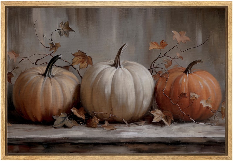 May include: A framed painting featuring three pumpkins in shades of orange and white. The pumpkins are arranged on a gray surface, with dried leaves and vines adding autumnal detail. The artwork is set against a muted background.