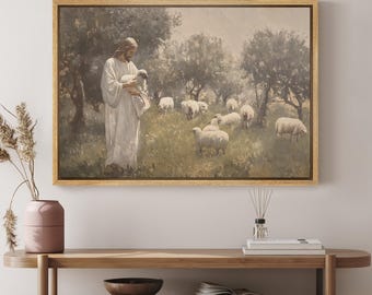 May include: A painting depicting Jesus holding a lamb in a field with a flock of sheep. The painting is framed in gold and features a soft, muted colour palette.
