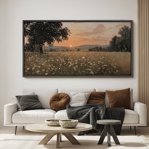 Puede incluir: Un cuadro de paisaje rectangular en un marco oscuro que representa una puesta de sol sobre un campo de flores silvestres blancas y hierba alta. Un gran &aacute;rbol se alza a la izquierda, mientras el horizonte muestra colinas bajo un cielo anaranjado.