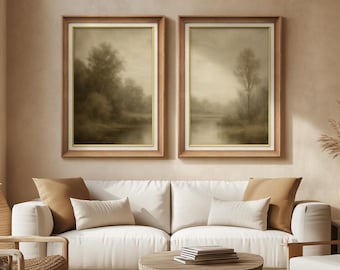 May include: Two framed landscape art prints. Each print features a sepia-toned scene of a misty lake and trees. The frames are a light brown wood with a gold inner border. The artwork hangs above a white sofa with neutral-toned throw pillows.